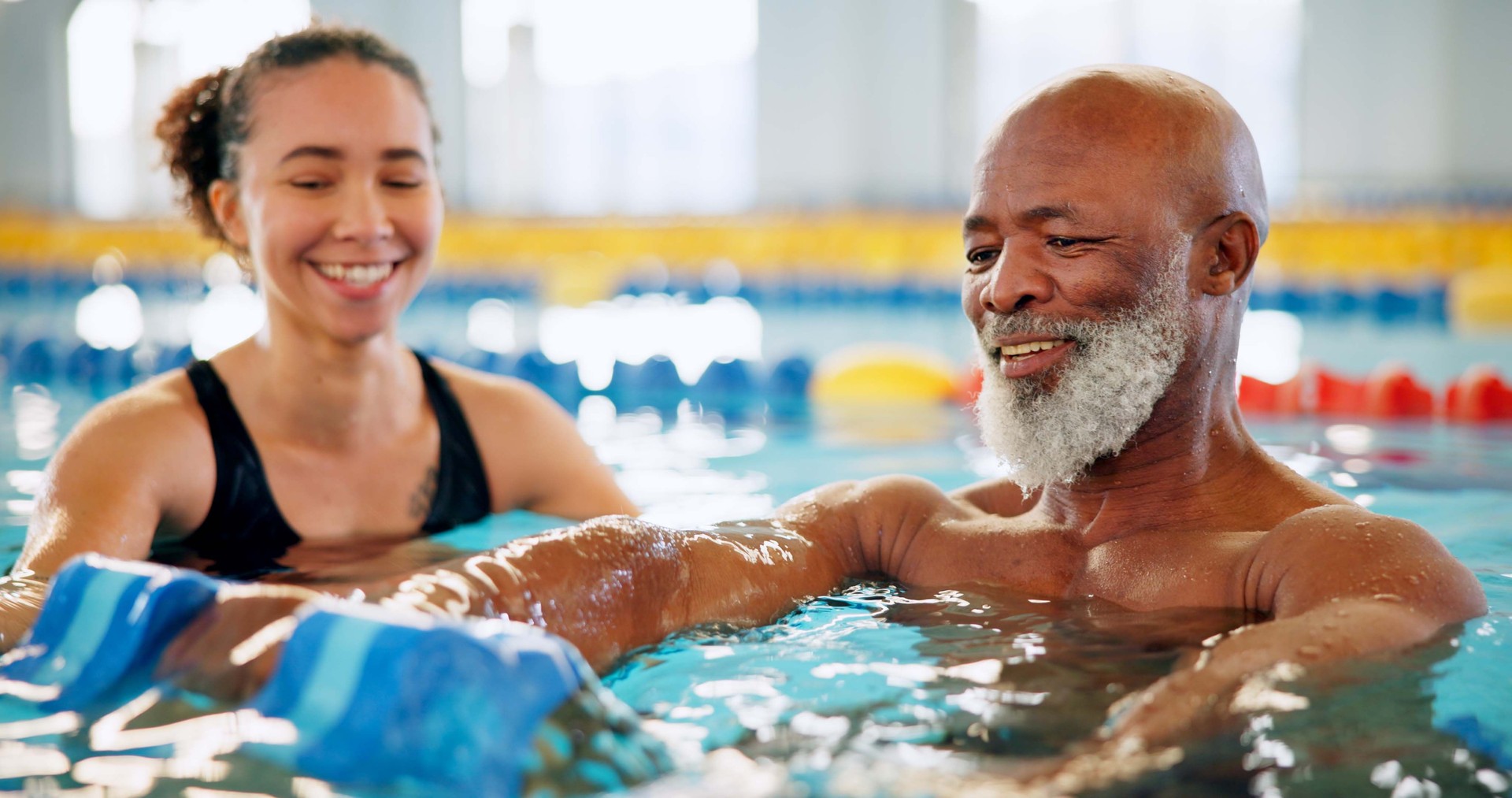 Dumbbell, help and mature man in swimming pool for exercise, healthy body and strong muscle. Aqua therapist, water and aerobics class for fitness, physiotherapy or rehabilitation of senior people